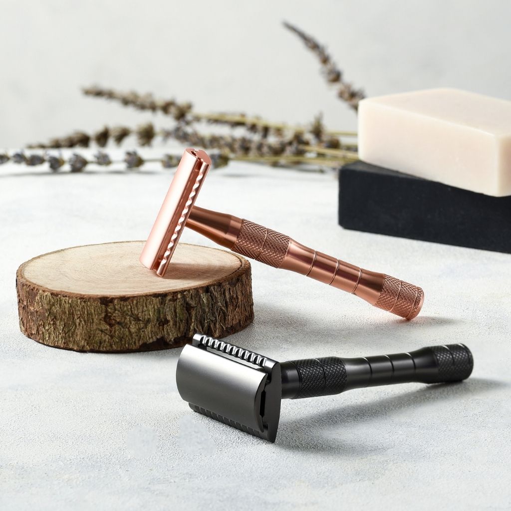 Jungle Culture rose gold and metallic black safety razors on table next to shaving soap bars